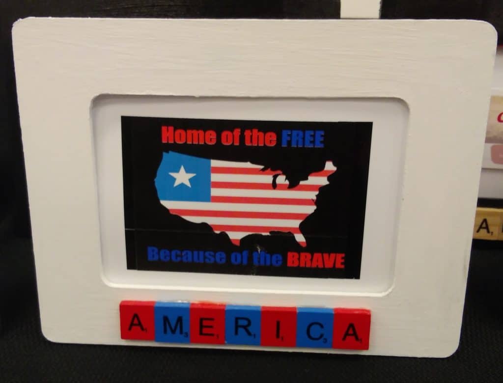 wooden picture frame painted white with letter tiles that spell America